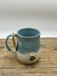 Blue ceramic mug with speckled design on a wooden surface