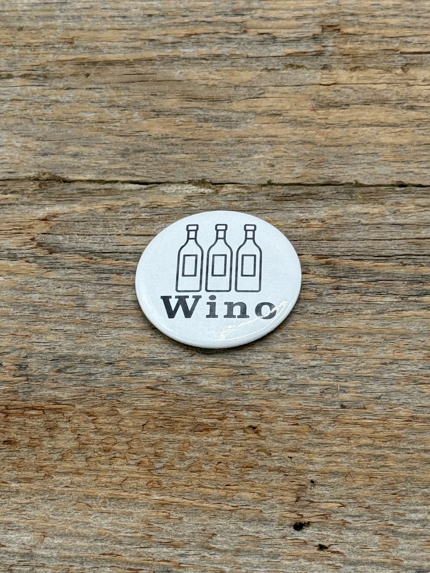 Magnet with 'Wino' branding on a wooden surface
